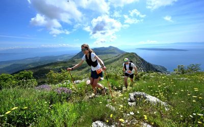 Tekač in tekačica na sončen pomladni dan tečeta po najvišjem grebenu tekaškega dogodka Tour de Hvar.