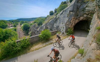 three cyclist on a road above the train tracks